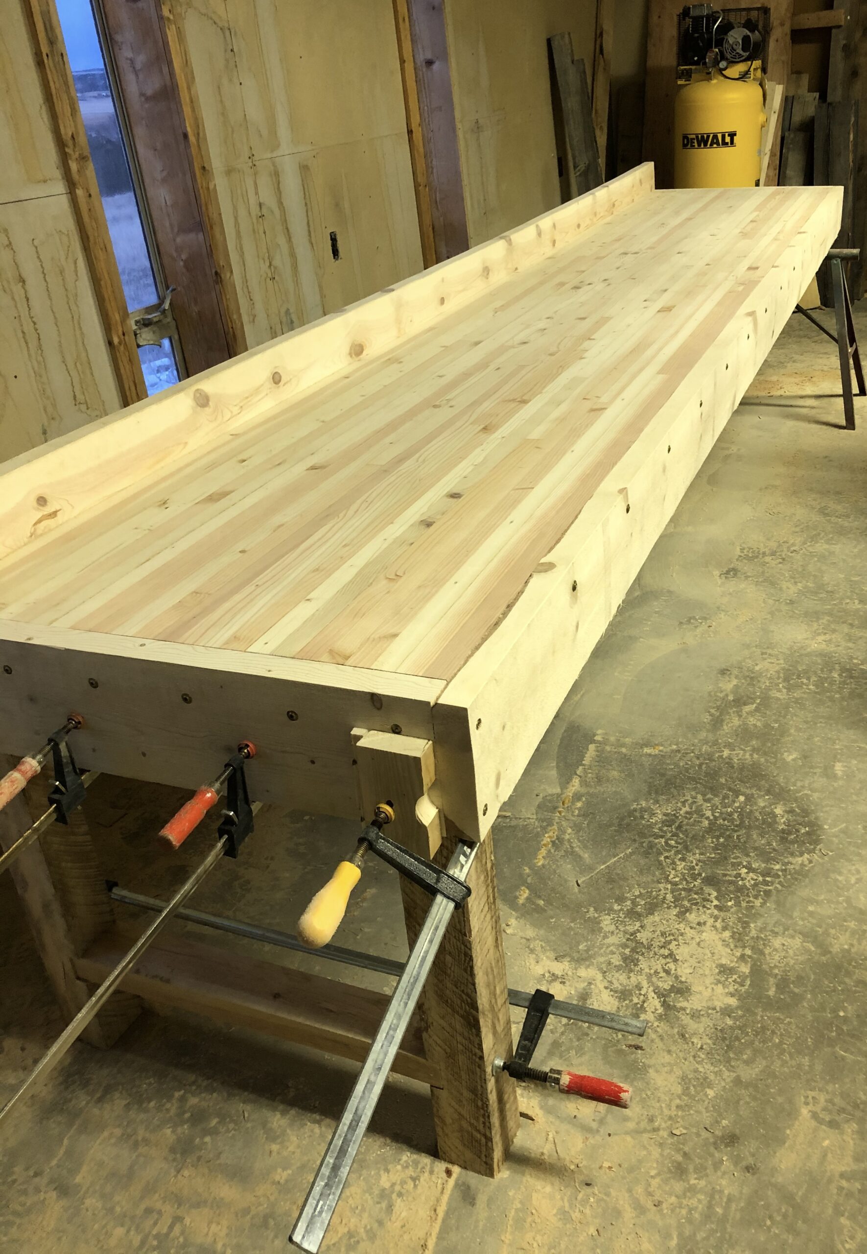 Lamination under full pressure — bar clamps, pipe clamps, color variation across the slab