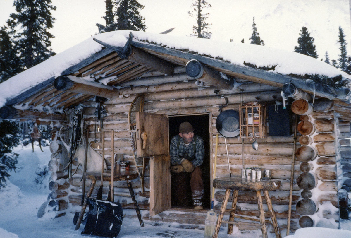 Dick Proenneke at the door of his hand-built cabin in winter at Twin Lakes Alaska