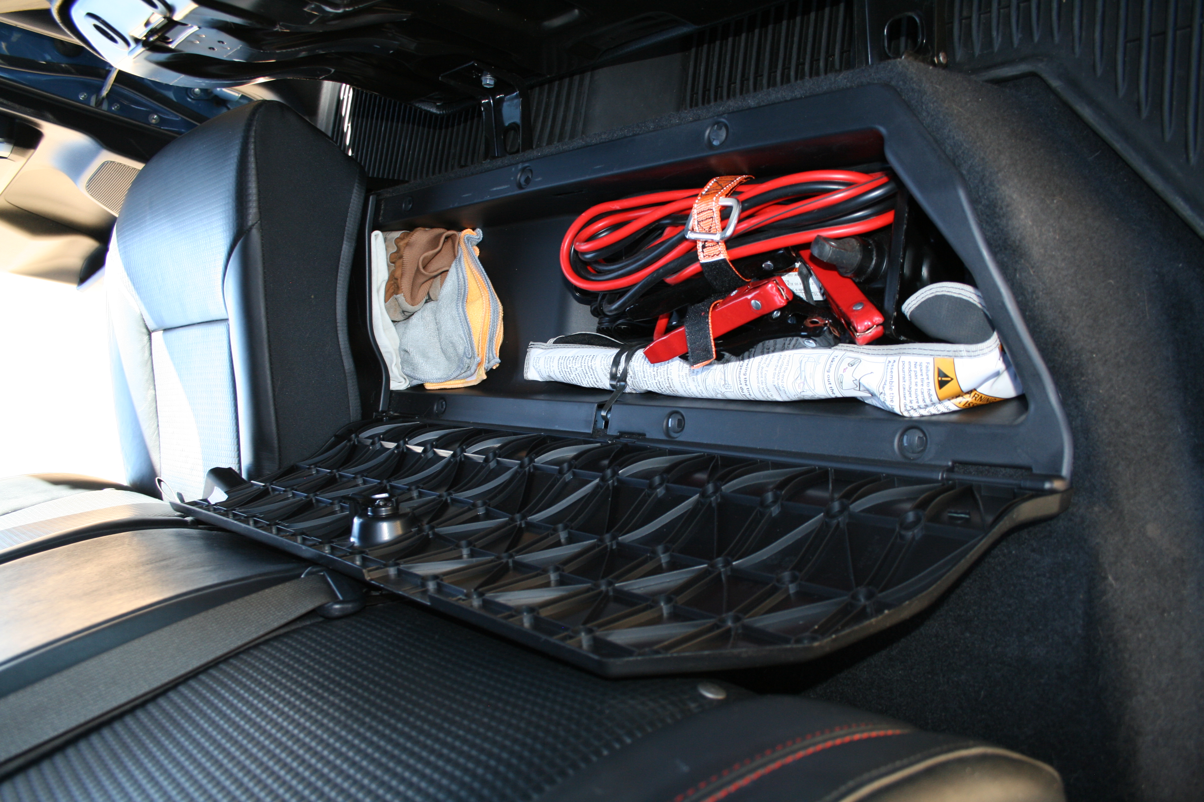 2018 Tacoma TRD Pro passenger side under rear seat storage showing jumper cables, jack, and shop rag