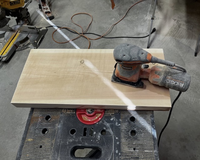 RIDGID palm sander on fresh-planed board — shaft of light across the surface