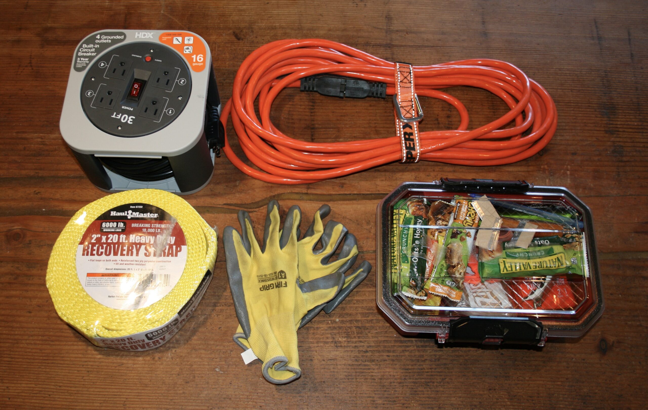 Tacoma TRD Pro passenger side behind seat flatlay showing Carhartt gloves, Hardy gloves, bear spray, recovery strap, and blanket