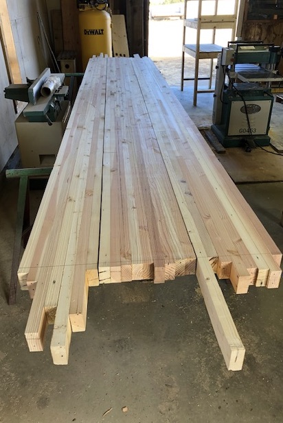 Sections out of clamps — pale, flat, honest. Full length of the shop