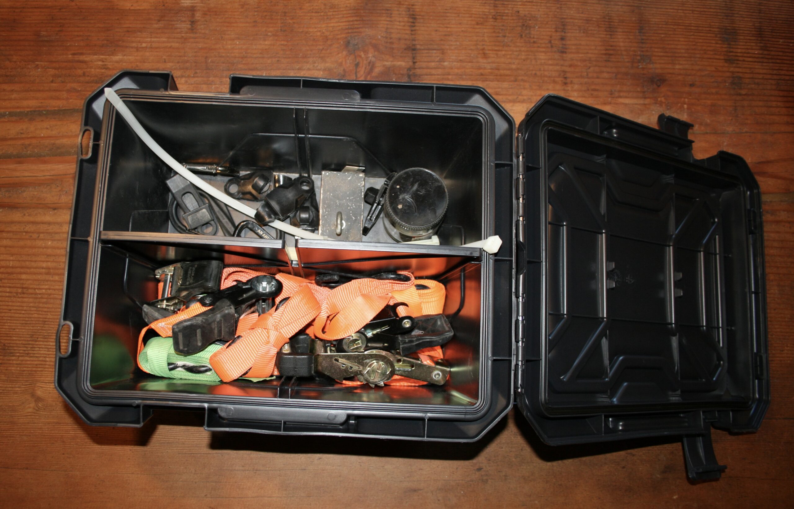 Plano hard case open showing ratchet straps and tie-down hardware inside